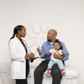 Royalty Free Photo of a Father Holding His Daughter Talking to a Pediatrician