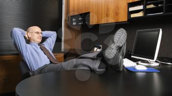 Royalty Free Photo of a Middle-aged Businessman in an Office Sitting With Feet on the Desk
