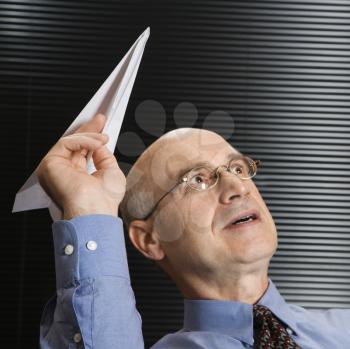 Royalty Free Photo of a Businessman Playing With a Paper Airplane