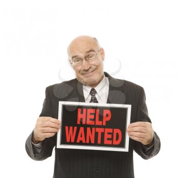 Royalty Free Photo of a Middle-aged Businessman Holding Up a Help Wanted Sign