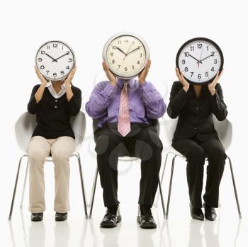 Royalty Free Photo of Businesspeople Sitting Holding Clocks Over Their Faces 