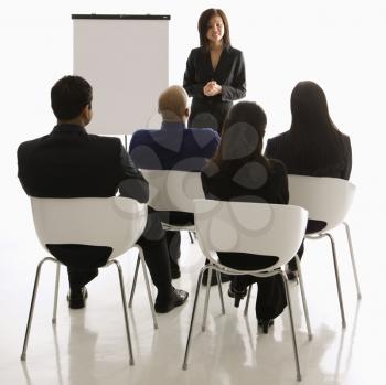 Royalty Free Photo of a Woman Standing in Front of a Business Group Leading a Presentation