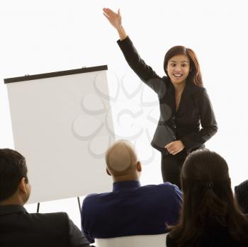 Royalty Free Photo of a Woman Standing in Front of a Business Group Pointing to a Presentation