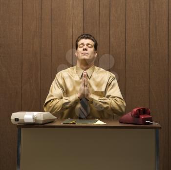 Royalty Free Photo of a Businessman Sitting at a Desk Praying