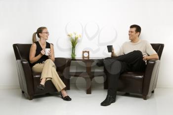 Royalty Free Photo of a Man and Woman Sitting in Armchairs Drinking Coffee