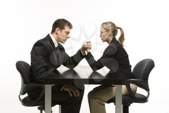 Royalty Free Photo of a businessman and businesswoman arm wrestling on table