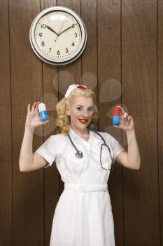 Royalty Free Photo of a Nurse Standing Holding Over Sized Pills and Smiling