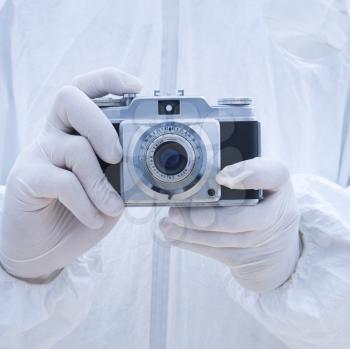 Royalty Free Photo of a Man in a Biohazard Suit Holding an Antique Camera