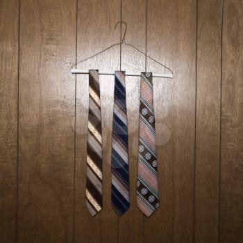 Royalty Free Photo of Three Retro Ties Hanging on a Wire Hanger Against Wood Paneling