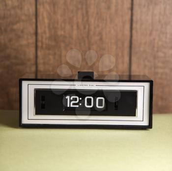 Royalty Free Photo of a Retro Alarm Clock Set for 12:00 Against Wood Paneling