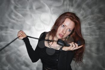 Royalty Free Photo of a Pretty Redheaded Woman Holding a Telephone Receiver to Her Ear