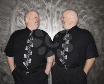 Royalty Free Photo of Bald Identical Twin Men Standing Together Laughing