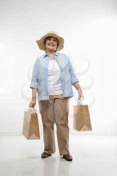 Royalty Free Photo of a Middle-Aged Woman Holding Gift Bags and Smiling