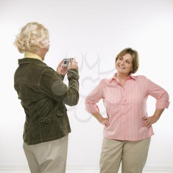 Royalty Free Photo of a Middle-Aged Woman Taking a Photo With a Digital Camera of a Senior Woman