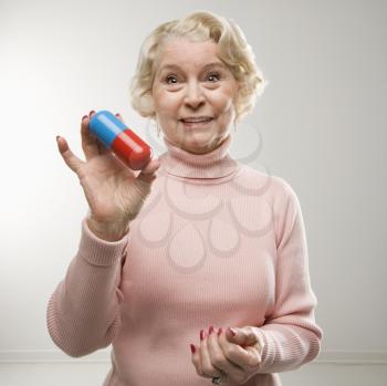 Royalty Free Photo of an Older Woman Holding an Over-sized Pill