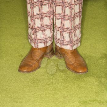 Royalty Free Photo of a Man's Legs in Plaid Pants Standing on a Retro Carpet