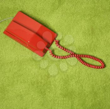 Royalty Free Photo of a Red Vintage Telephone on a Green Carpet