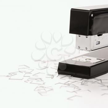 Royalty Free Photo of a Black Stapler on a White Background Surrounded by Individual Staples