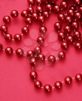 Royalty Free Photo of a String of Red Beads on a Red Background