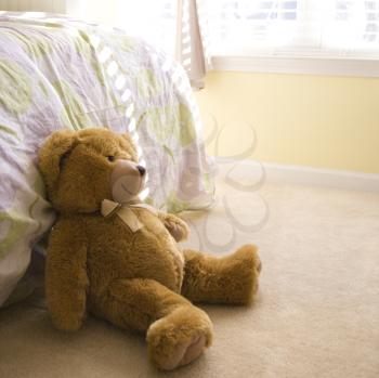 Royalty Free Photo of a Plush Brown Teddy Bear on a Bedroom Floor