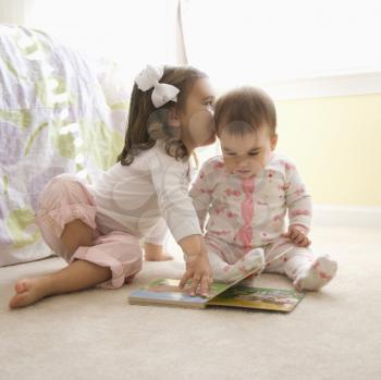 Royalty Free Photo of Little Girls Sitting on the Bedroom Floor Looking at a Book