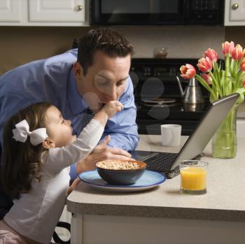 Royalty Free Photo of a Little Girl Feeding Her Father Cereal 