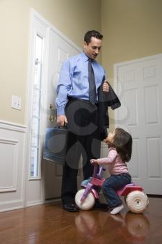 Royalty Free Photo of a Businessman at a Door With a Briefcase With a Daughter Looking Up at Him