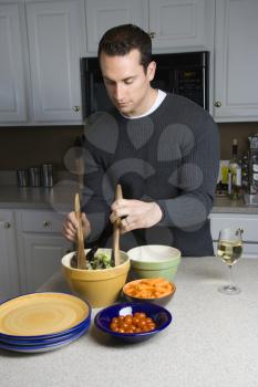 Royalty Free Photo of a Man Making Salad on the Kitchen Counter