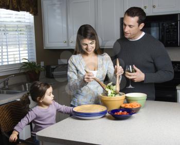 Royalty Free Photo of a Woman Making Salad on Kitchen Counter with Her and Husband