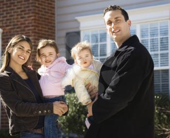 Royalty Free Photo of a Family Standing in Front of a House