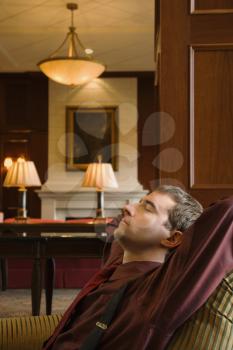 Royalty Free Photo of a Businessman Reclining With Arms Behind  His Head and Eyes Closed