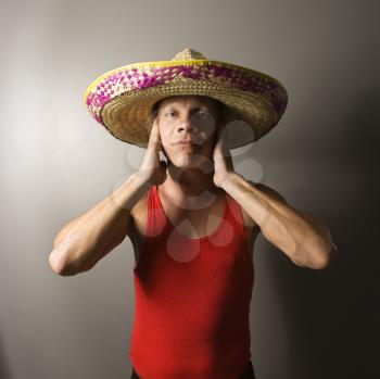 Royalty Free Photo of a Male Wearing a Sombrero With Hands Over His Ears