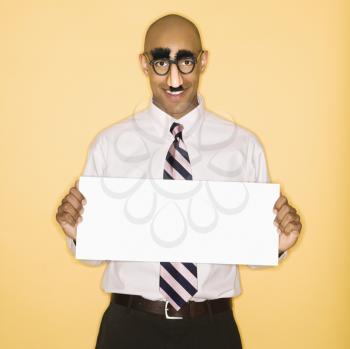 Royalty Free Photo of a Man Wearing a Groucho Mask Disguise Holding a Blank Sign