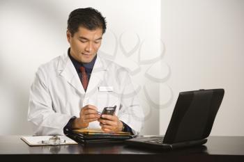 Royalty Free Photo of a Doctor Sitting at a Desk With Charts and a Laptop
