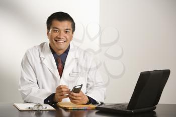 Royalty Free Photo of a Doctor Sitting at a Desk With Charts and a Laptop