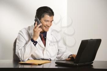 Royalty Free Photo of a Physician Sitting at a Desk With a Laptop Computer