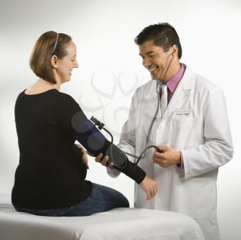 Royalty Free Photo of a Male Doctor Testing the Blood Pressure of Pregnant Woman