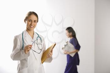 Royalty Free Photo of a Doctor Smiling With a Physician's Assistant Walking by in the Background