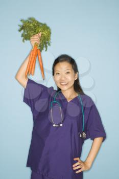 Royalty Free Photo of a Doctor Holding up a Bunch of Carrots