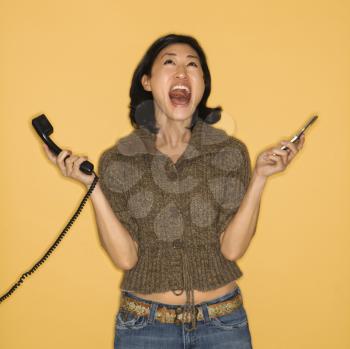 Royalty Free Photo of a Woman Holding a Telephone and Cellphone With Mouth Open