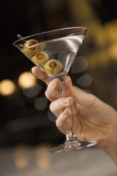 Royalty Free Photo of a Female's Hand Holding a Martini With Three Olives
