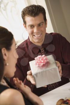 Royalty Free Photo of a Man Presenting a Wrapped Gift to a Surprised Woman at a Restaurant