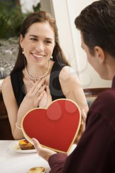 Royalty Free Photo of a Man Giving a Heart Shaped Box of Chocolates to Woman at a Restaurant