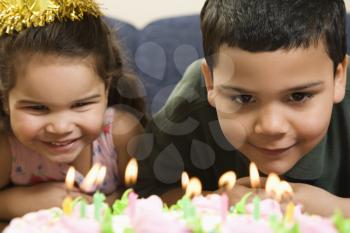 Royalty Free Photo of a Girl and Boy Leaning in Close Looking at Lit Candles on a Birthday Cake and Smiling