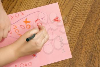 Royalty Free Photo of a Child Drawing on a Paper with Crayons