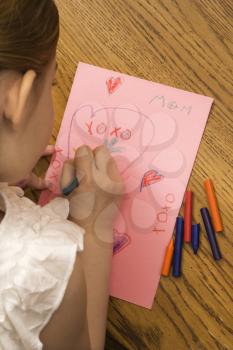 Royalty Free Photo of a Child Drawing on a Paper with Crayons