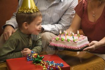 Royalty Free Photo of a Boy in a Party Hat With a Birthday Cake and Family