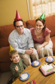 Royalty Free Photo of a Boy and Parents in Party Hats Eating Birthday Cake