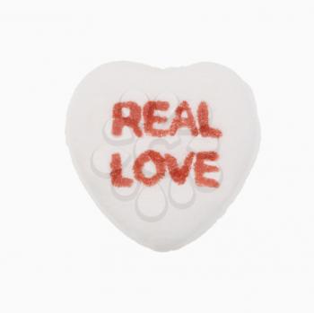 Royalty Free Photo of a White Candy Heart That Reads Real Love