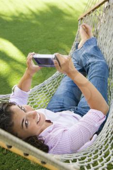 Royalty Free Photo of a Woman Holding a PDA While Lying in a Hammock